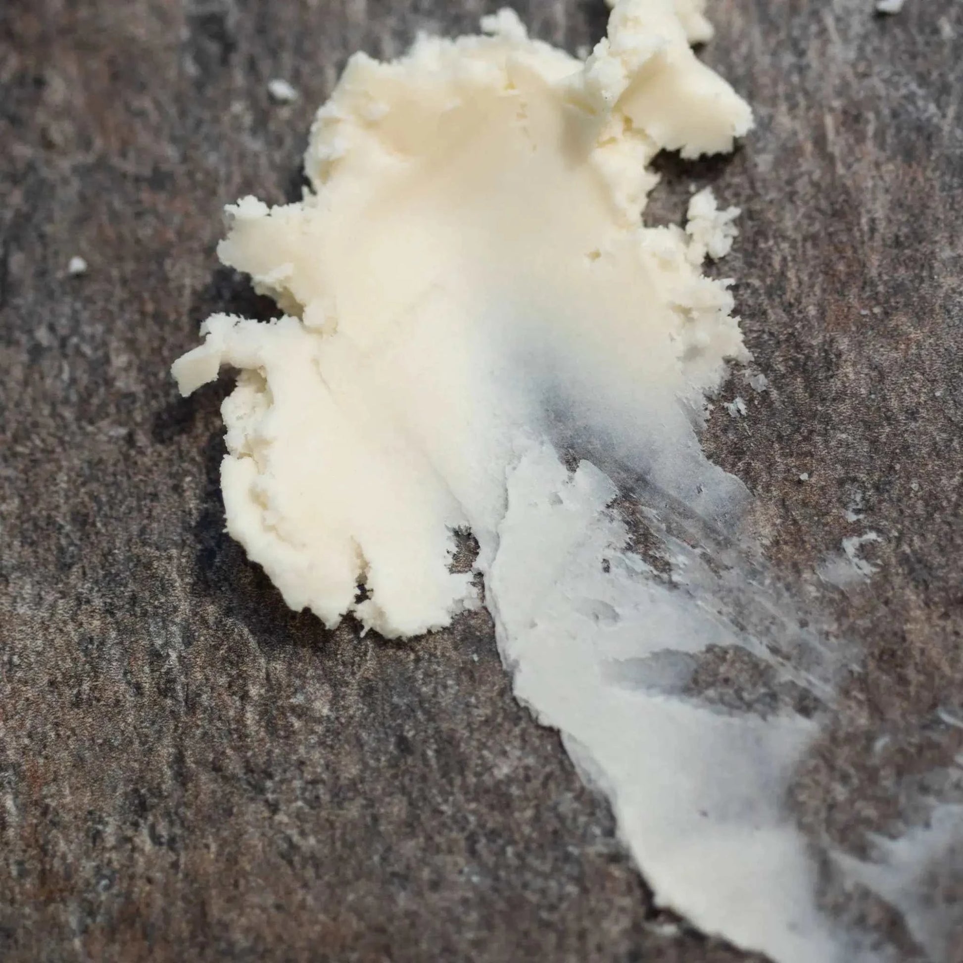Pure semi-solid mango butter bulk smear on dark textured surface for skin and haircare use