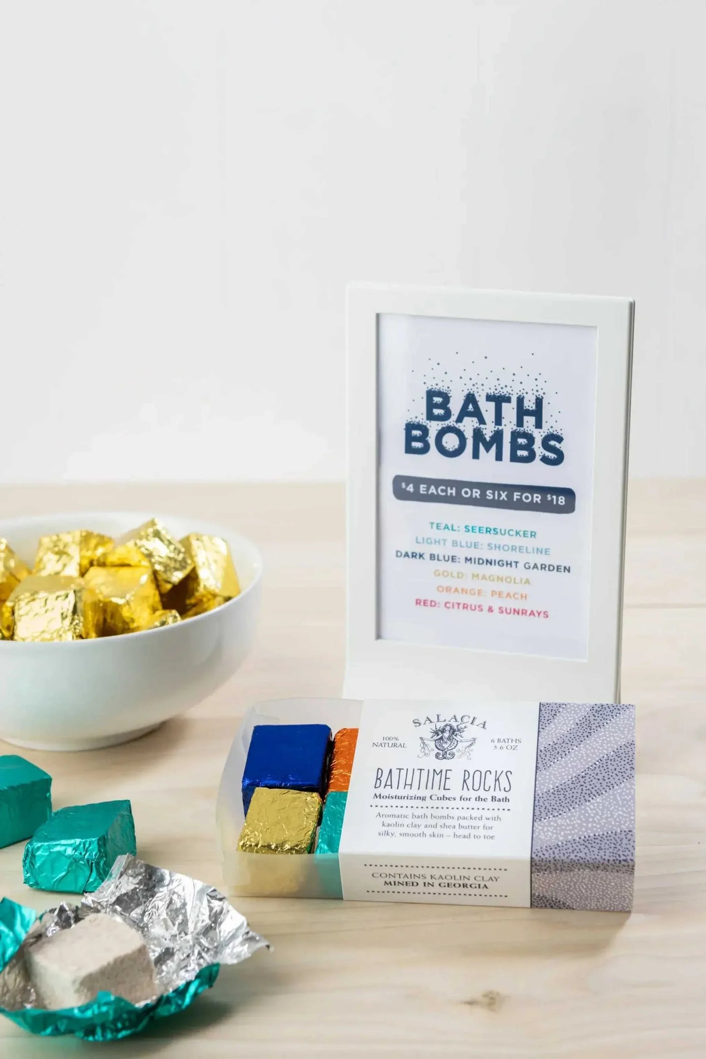 BathTime Rocks moisturizing aromatic bath cubes in assorted scents with colorful foil wrapping displayed with signage and bowl on wooden table