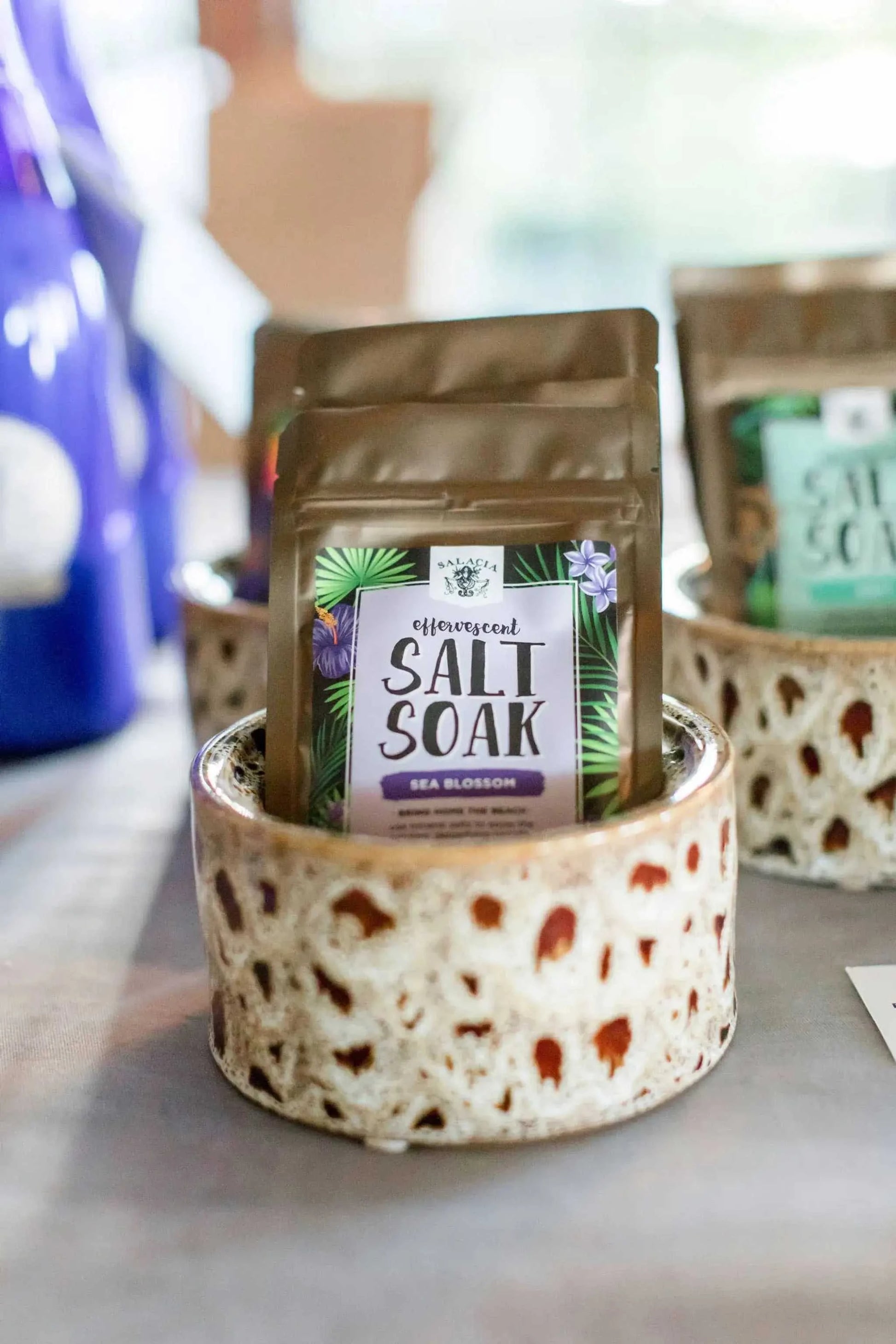 Effervescent salt soak pouches displayed in a coastal-themed holder.